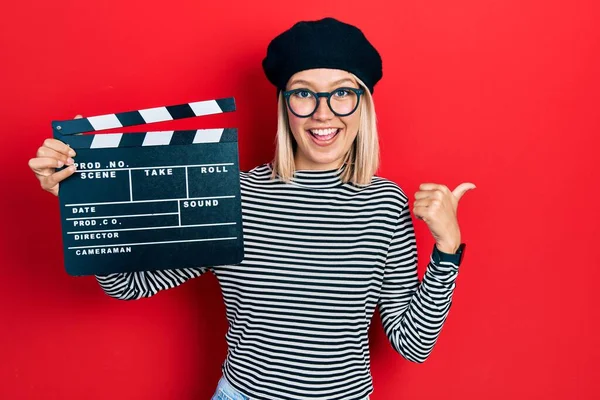 Piękna Blondynka Trzyma Wideo Film Clapboard Wskazując Kciuk Góry Bok — Zdjęcie stockowe