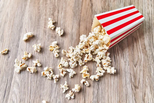 Pack Salty Popcorns Falling Wooden Surface — Stock Photo, Image