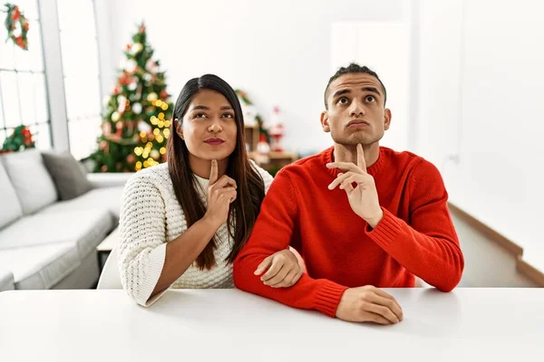 Young Latin Couple Sitting Table Christmas Tree Thinking Concentrated Doubt — 图库照片