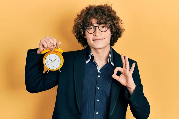 Handsome Young Man Wearing Business Jacket Holding Clock Doing Sign — Stockfoto