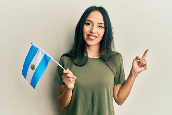 Mladá Hispánská Dívka Drží Argentinskou Vlajku Úsměvem Šťastně Ukazuje Rukou — Stock fotografie