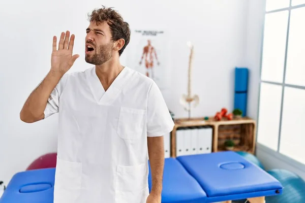 Young Handsome Physiotherapist Man Working Pain Recovery Clinic Shouting Screaming — Φωτογραφία Αρχείου
