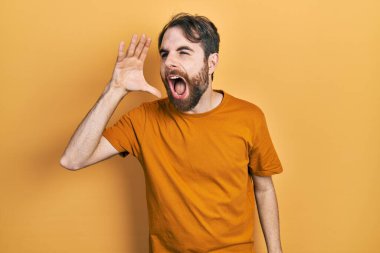 Sakallı, sıradan sarı tişörtlü beyaz bir adam bağırıyor ve ağızdan ağıza bağırıyor. iletişim konsepti. 