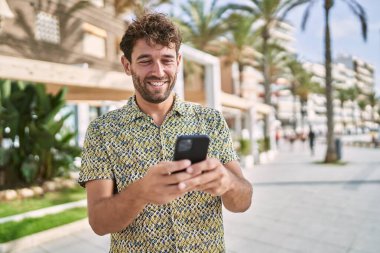 Sokakta akıllı telefon kullanan, kendine güvenen genç bir İspanyol.