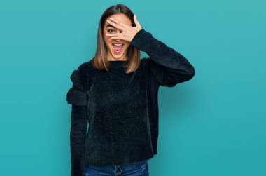 Zarif bir süveter giyen güzel esmer kadın. Şoka girip yüzünü ve gözlerini kapayarak utanmış bir ifadeyle parmaklarından bakıyor.. 