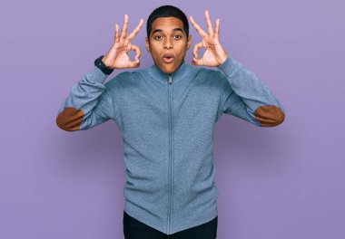 Gündelik kazak giyen genç, yakışıklı İspanyol adam şaşırmış ve şaşırmış görünüyor. çılgın ifade 