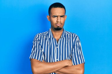 Gündelik kıyafetler giyen, kuşkucu ve gergin genç Afro-Amerikalı bir adam. Yüzünde çapraz kollarla onaylamayan bir ifade var. negatif kişi. 