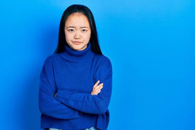 Gündelik kıyafetler giyen genç Çinli kız şüpheci ve gergin, yüzünde çapraz kollu tasvip etmeyen ifade. negatif kişi. 