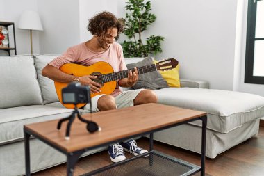 Evde klasik gitar çalan Latin asıllı genç bir adam kayıt yapıyor..