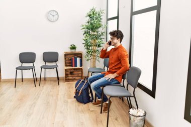 Young hispanic man smiling confident talking on the smartphone at waiting room