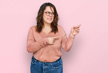 Gündelik kıyafet ve gözlük takan genç ve cüsseli bir kadın iki eli de endişeli ve şaşırmış bir ifade takınıyor. 