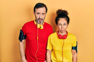 Orta yaşlı bir çift İspanyol kadın ve erkek spor giysisi ve kol bandı takıyor. Depresyonda ve endişe içindeler. Kızgın ve korkmuş ağlıyorlar. hüzünlü ifade. 