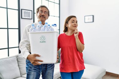 Orta yaşlı bir çift ellerinde plastik şişelerle geri dönüşüm kutusunu tutarken ciddi bir yüz ifadesi var. Elleri çenesinde soru sormayı düşünüyorlar. Kafa karıştırıcı bir fikir. 