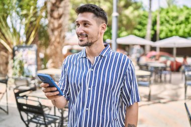 Parkta akıllı telefon kullanan genç yakışıklı adam.