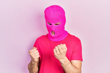 Modern boyalı saçlı, pembe kar maskesi takan genç İspanyol adam kolları havada ve gözleri kapalı bir şekilde başarıyı kutluyor ve şaşırıyor. 