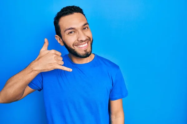 髭を生やしたヒスパニック系の男性は 携帯電話で話すような手や指で携帯電話のジェスチャーを行う笑顔カジュアルブルーのTシャツを着ていた コミュニケーションの概念 — ストック写真