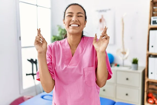 Jonge Spaanse Vrouw Die Werkt Pijnkliniek Gekruiste Vinger Die Glimlacht — Stockfoto