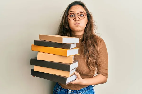 Young Hispanic Girl Holding Pile Books Puffing Cheeks Funny Face — Stock Photo, Image