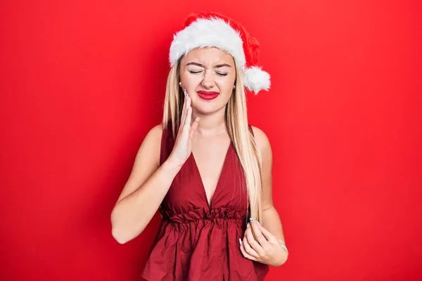 Молодая Блондинка Рождественской Шляпе Трогает Рот Рукой Болезненным Выражением Лица — стоковое фото