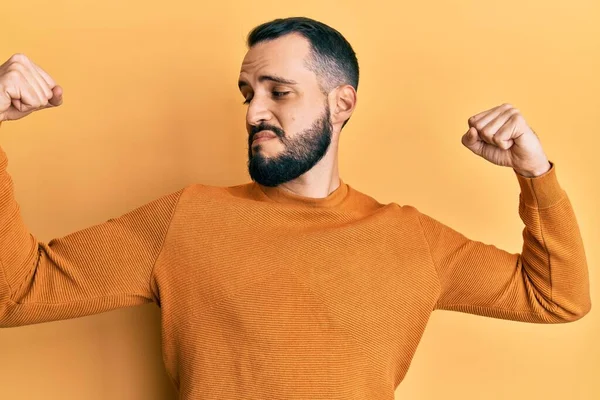 腕の筋肉を示すカジュアルな冬のセーターを着て髭を生やして若い男は誇りに思って笑う フィットネスのコンセプト — ストック写真