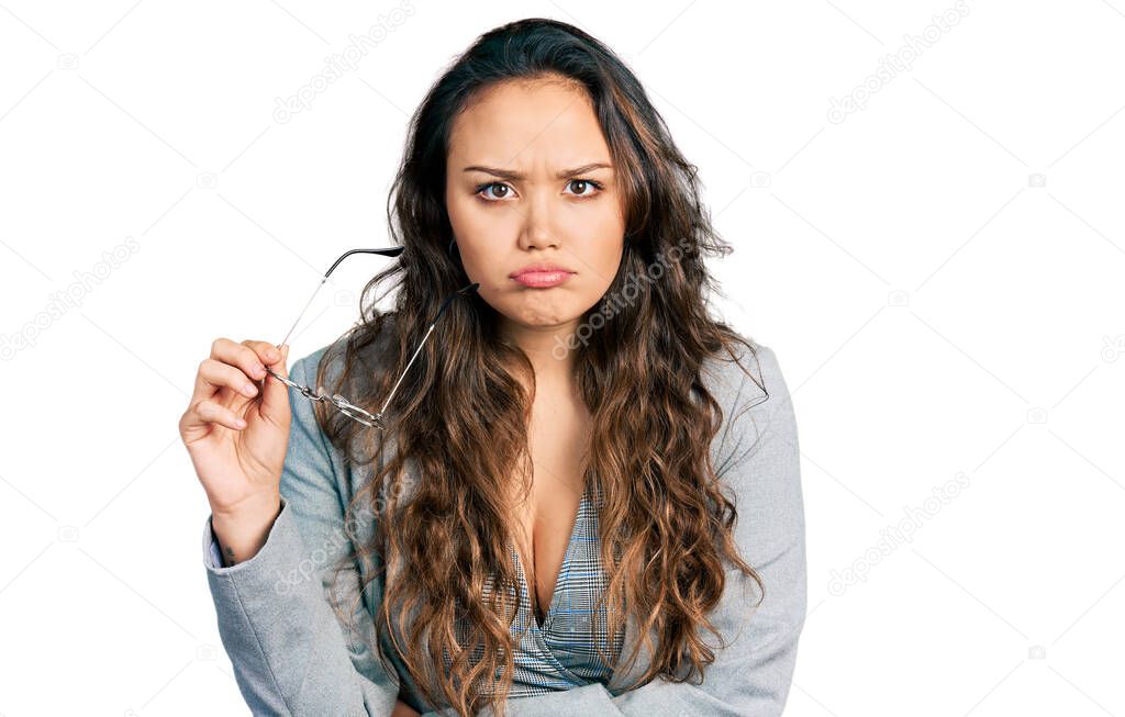 Young hispanic girl wearing business clothes holding glasses skeptic and nervous, frowning upset because of problem. negative person. 