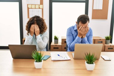 Orta yaşlı İspanyol kadın ve erkek ofiste dizüstü bilgisayarıyla oturup ağlarken suratını ellerle kapatıyor. depresyon kavramı. 