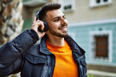 Sakallı yakışıklı, neşeli ve kendine güvenen, kışlık palto ve kulaklık takan bir İspanyol.