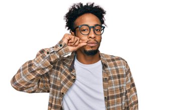 Sakallı, sıradan kıyafetler, gözlük takan ağzı ve dudakları parmaklarıyla kapanmış genç Afro-Amerikan bir adam. gizli ve sessiz, tabu konuşması 