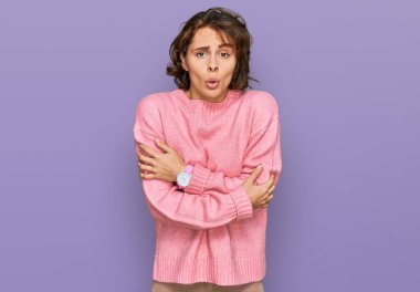 Latin kökenli genç bir kadın günlük kıyafetler giyiyor. Kış soğuğu için titriyor ve donuyor. Yüzünde üzgün ve şok ifadesi var. 
