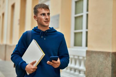 Üniversitede akıllı telefon kullanan genç sarışın bir öğrenci..