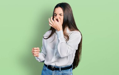 Genç esmer genç iş adamı beyaz gömleği giyiyor. Pis ve iğrenç bir koku alıyor. Nefesini burnunda tutuyor. Kötü kokuyor. 