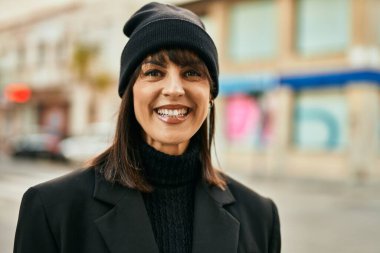 Genç İspanyol kadın gülümseyerek şehirde mutlu mesut dikiliyor..