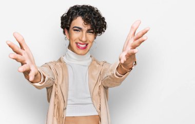 Handsome man wearing make up and woman clothes looking at the camera smiling with open arms for hug. cheerful expression embracing happiness. 