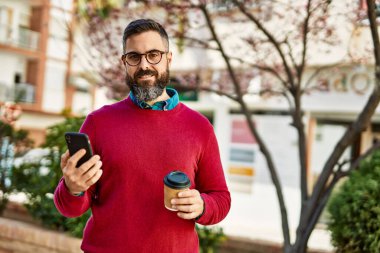 Genç İspanyol yönetici akıllı telefon kullanıyor ve şehirde kahve içiyor..