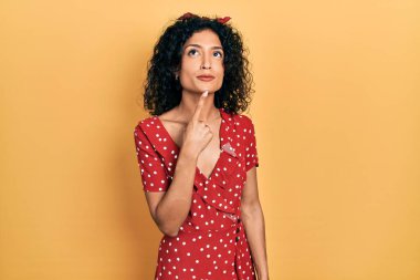 Yazlık elbise giyen genç Latin kız şüphe üzerine yoğunlaşmıştı. Parmakları çenesinde ve yukarı bakıyordu. 