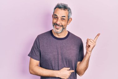 Handsome middle age man with grey hair wearing casual t shirt smiling happy pointing with hand and finger to the side 
