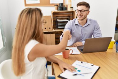 İki iş adamı ofiste el sıkışarak mutlu bir kutlama yapıyor..