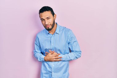 Sakallı İspanyol bir adam midesi üstünde sıradan mavi bir gömlek giyiyor çünkü hazımsızlık, acı verici bir hastalık ve kendini iyi hissetmiyor. Ağrı kavramı. 