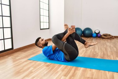 Yakışıklı İspanyol adam egzersiz yapıyor ve yoga minderinde geriniyor. Spor salonunda esneklik ve antrenman yapıyor.