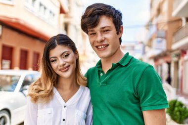 Genç, beyaz bir çift, mutlu bir şekilde gülümsüyor ve şehirde birbirlerine sarılıyorlar..