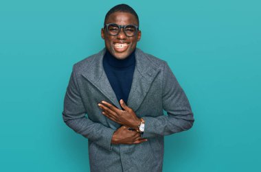 İş kıyafetleri ve gözlük takan genç Afrikalı Amerikalı adam gülümseyerek kahkahalarla gülüyor.. 