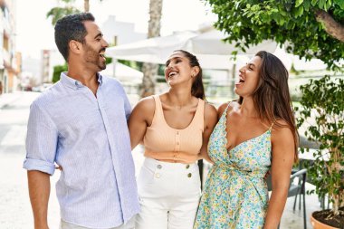 Üç İspanyol arkadaş şehirde mutlu bir şekilde gülüyor ve sarılıyorlar..