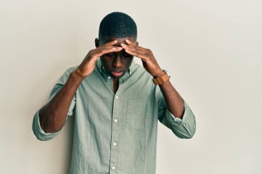 Genç Afro-Amerikan adam stres yüzünden elleri başının üstünde gündelik giysiler giyiyor. migren ağrısı. 
