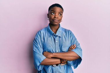 Kollarını kavuşturmuş genç Afrikalı Amerikalı kadın gülümsüyor ve başka tarafa bakıyor.. 