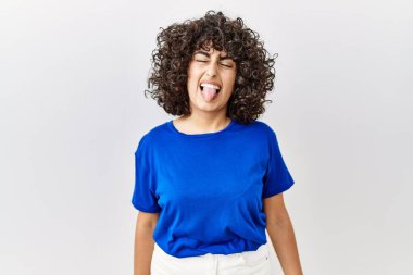 Ortadoğulu genç bir kadın izole edilmiş arka planda duruyor. Komik bir ifadeyle dilini dışarı çıkarıyor. duygu kavramı. 