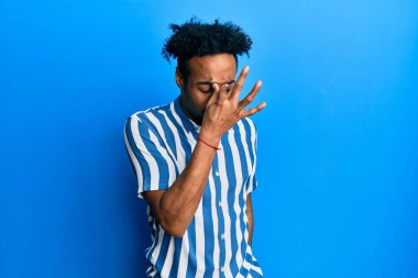 Sakallı, sıradan çizgili gömlek giyen, burnu ve gözleri ovuşturmaktan yorgun düşmüş yorgun ve başı ağrıyan Afrikalı genç bir Amerikalı. Stres ve hüsran kavramı. 