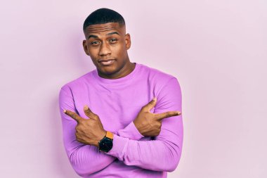 Gündelik pembe süveter giyen genç bir adam iki tarafı da parmaklarıyla işaret ediyor, farklı yönlerde farklı görüşler. 