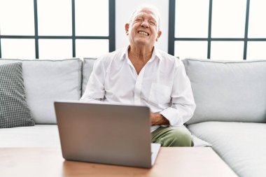 Evde dizüstü bilgisayar kullanan yaşlı bir adam midesi üstünde oturuyor çünkü hazımsızlık, acı veren bir hastalık kendini iyi hissetmiyor. Ağrı kavramı. 