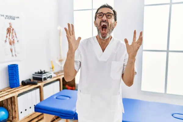 痛み回復クリニックで働く髭を生やした中年男性は狂った叫びと積極的な表情と腕を上げて叫びました フラストレーションコンセプト — ストック写真