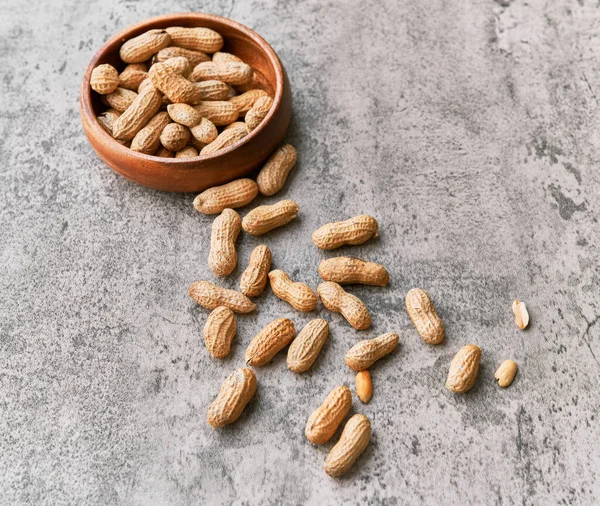 Beton bir yüzeyde kasede bir avuç fıstık.